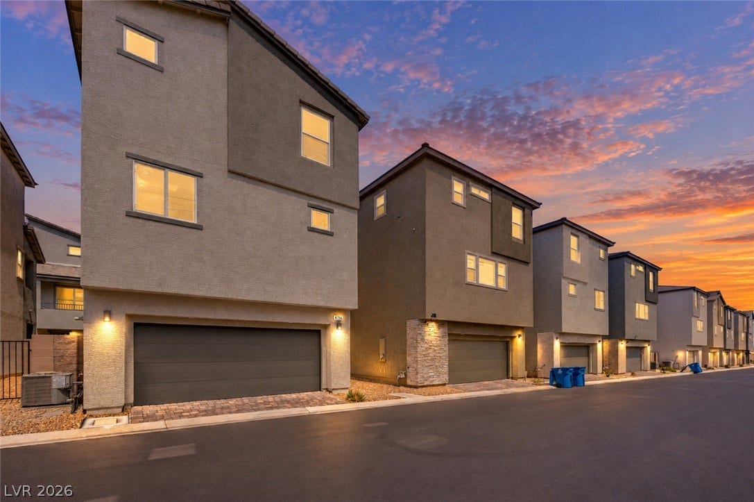 Modern multi-level townhomes showcase clean architectural lines and integrated garages under a sunset sky.