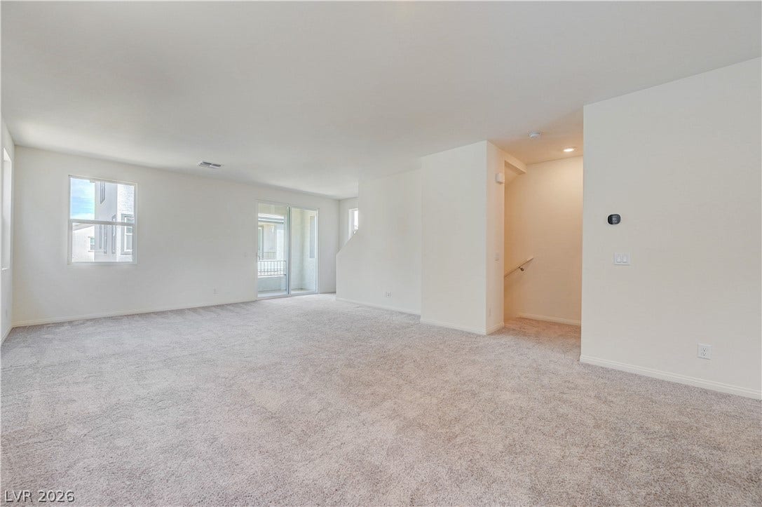 Plush carpeting and tall windows define this open second-floor living area.
