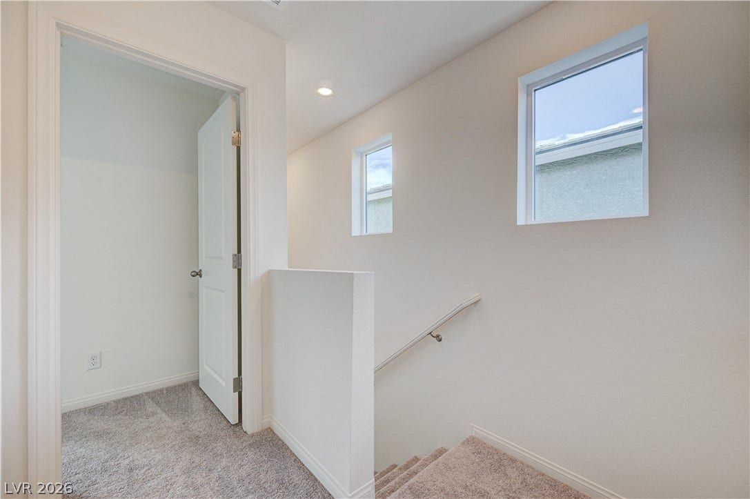 A light-filled landing and staircase showcase plush carpeting and clean architectural lines.