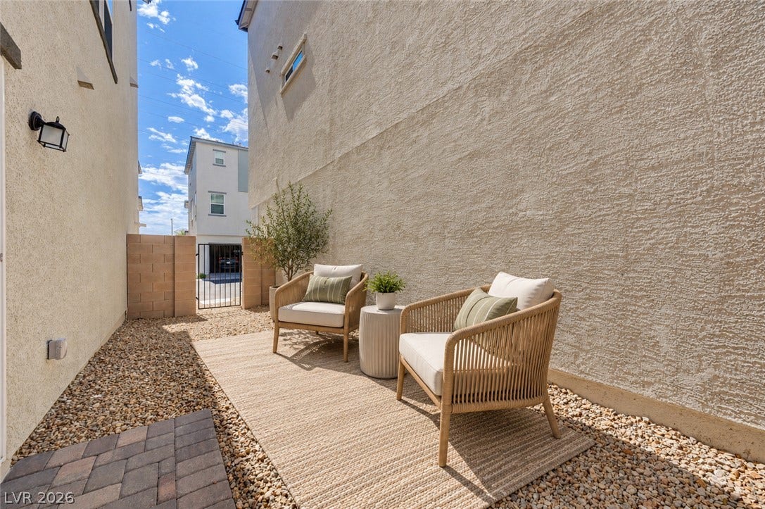 Textured stucco walls enclose a private, low-maintenance outdoor side yard layered with gravel and pavers.