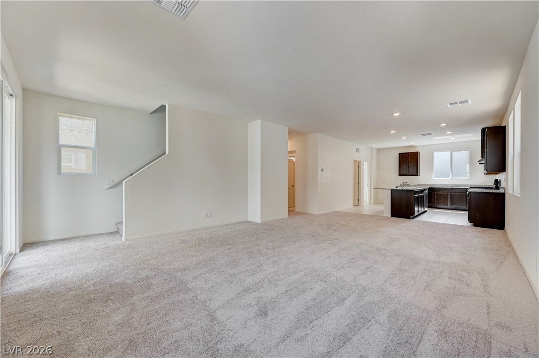 Plush carpeting anchors this airy open floorplan seamlessly connecting the living area to the kitchen.