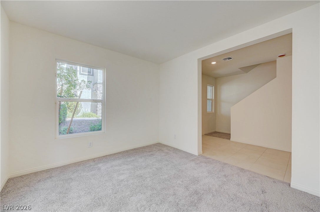 An open doorway connects a carpeted living space to a tiled entryway and stairs.
