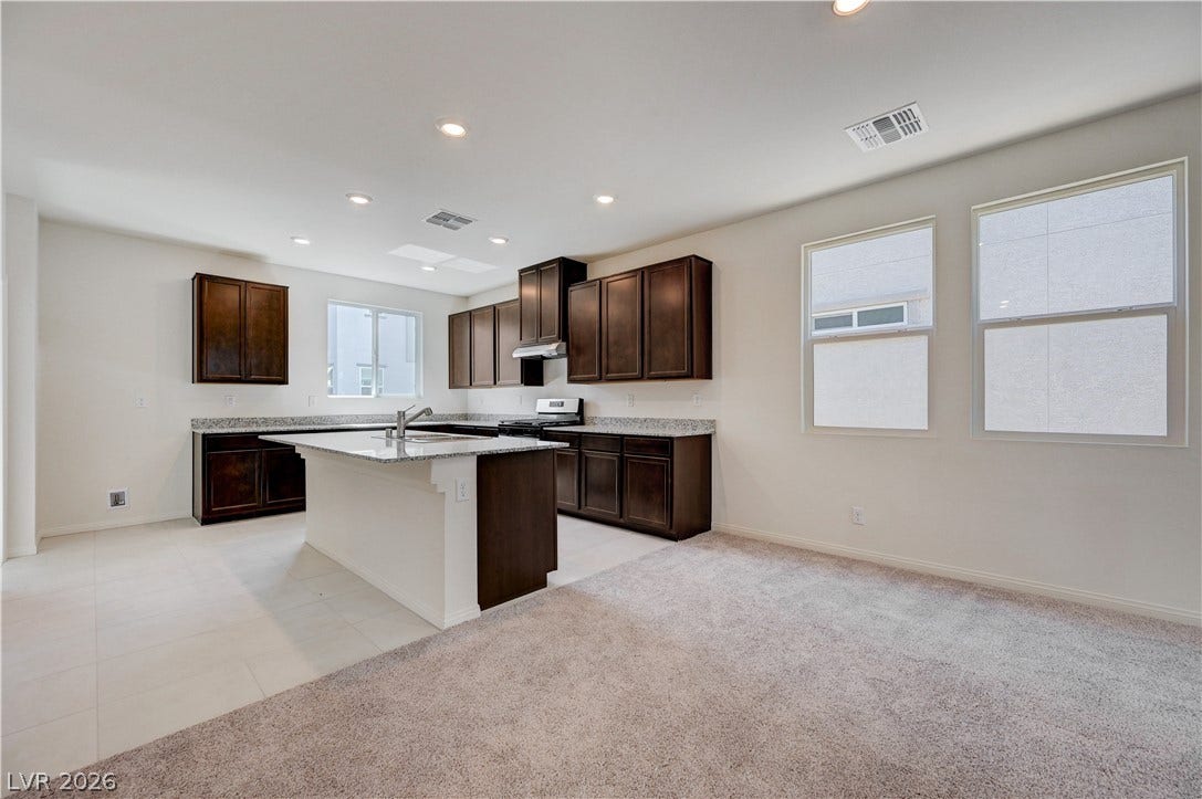 Rich cabinetry contrasts beautifully with granite countertops in this open kitchen space.