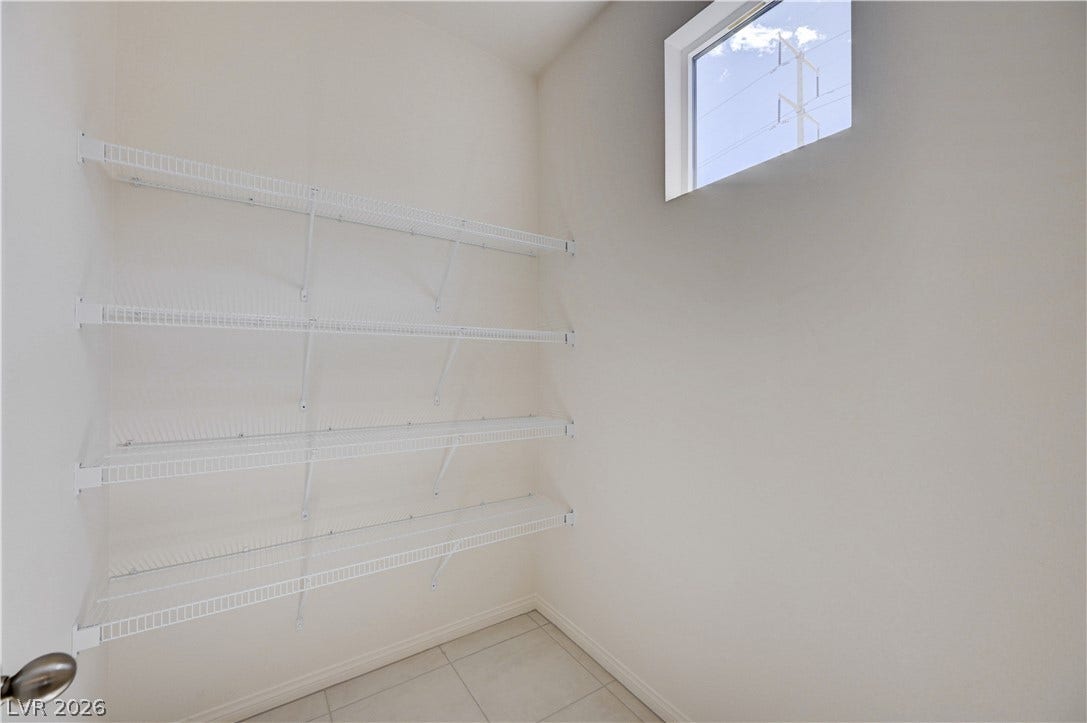 A high window brings natural light into this functional pantry space with built-in wire shelving.