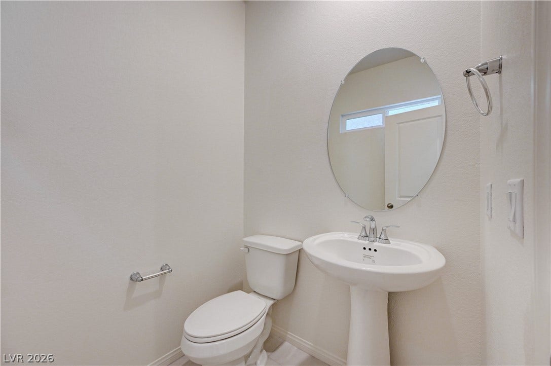 Minimalist design elements define this classic powder room containing a pedestal sink and oval mirror.