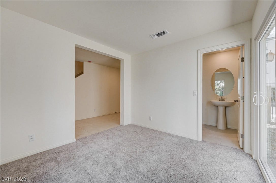 Plush carpeting and sliding glass doors define this versatile living space adjacent to a half bath.