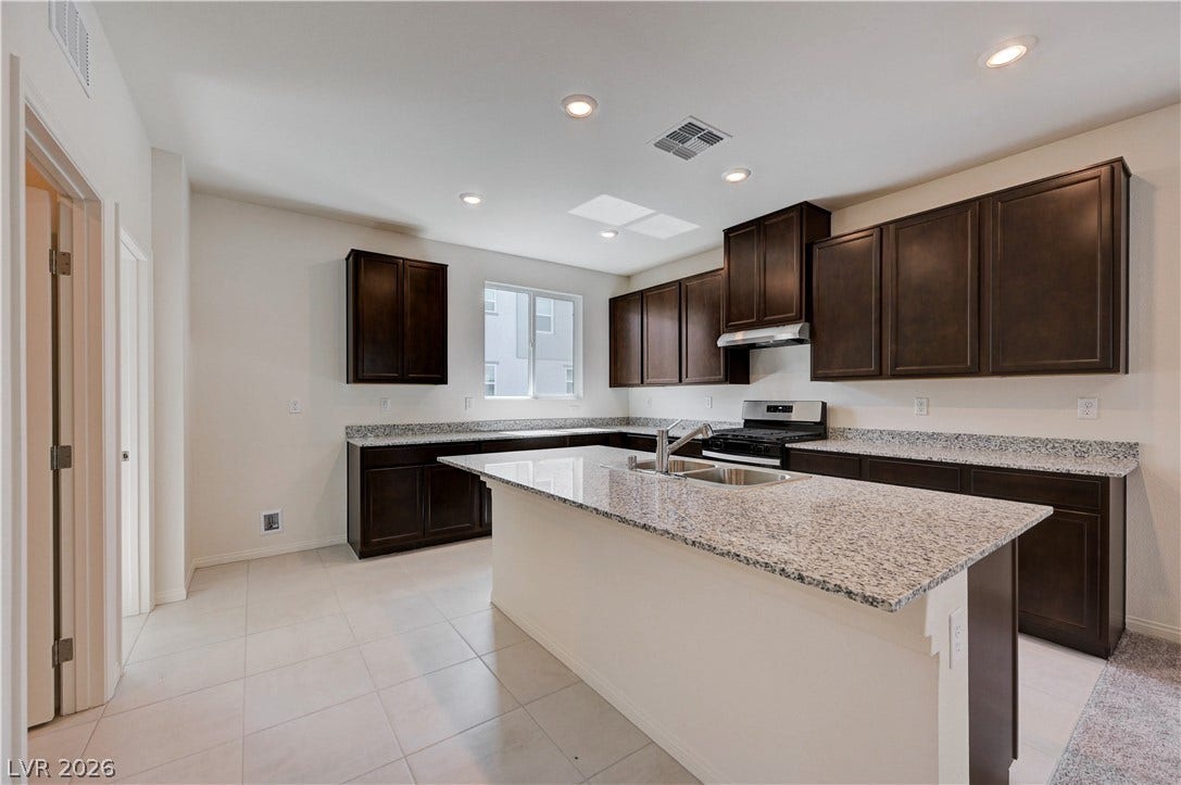 Polished granite countertops and classic dark cabinetry anchor this spacious, light-filled culinary space.