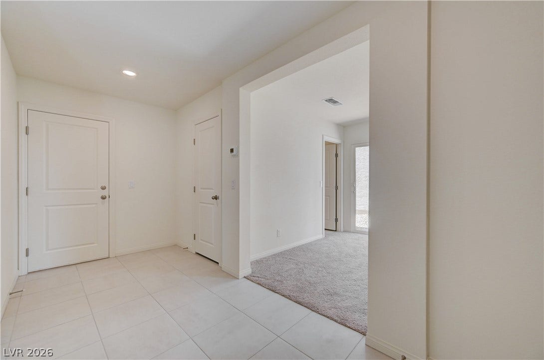 Tiled flooring and a wide archway lead from the foyer into carpeted living spaces.