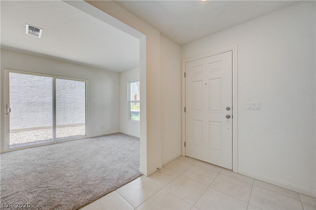 Tiled flooring greets guests at the entryway, transitioning into a carpeted living space.