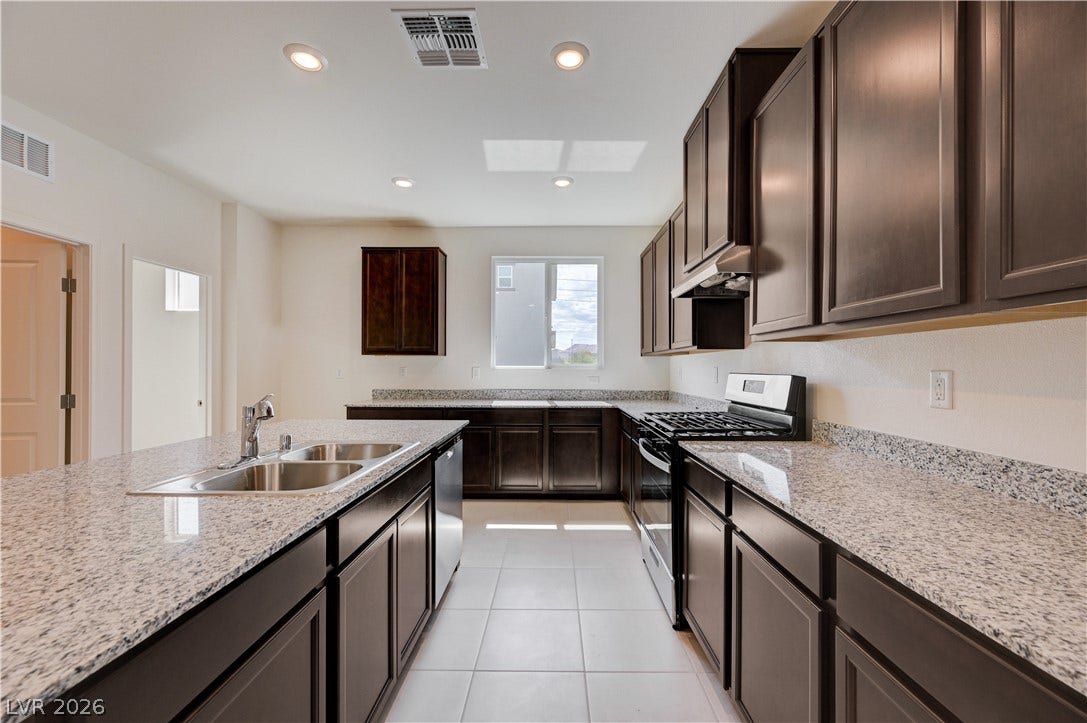 Gleaming granite countertops pair beautifully with rich dark cabinetry and sleek tile flooring.