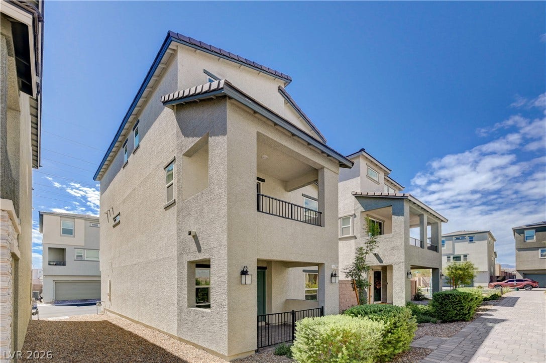 A modern multi-level exterior displays clean stucco finishes under a bright blue sky.
