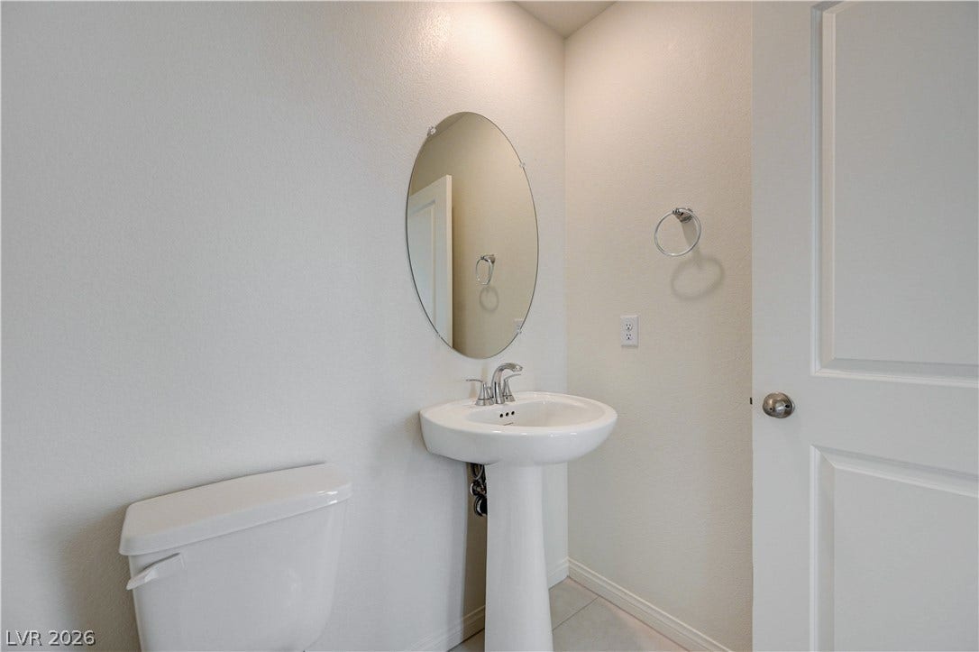 A classic pedestal sink pairs with light-toned tile flooring in this powder room.