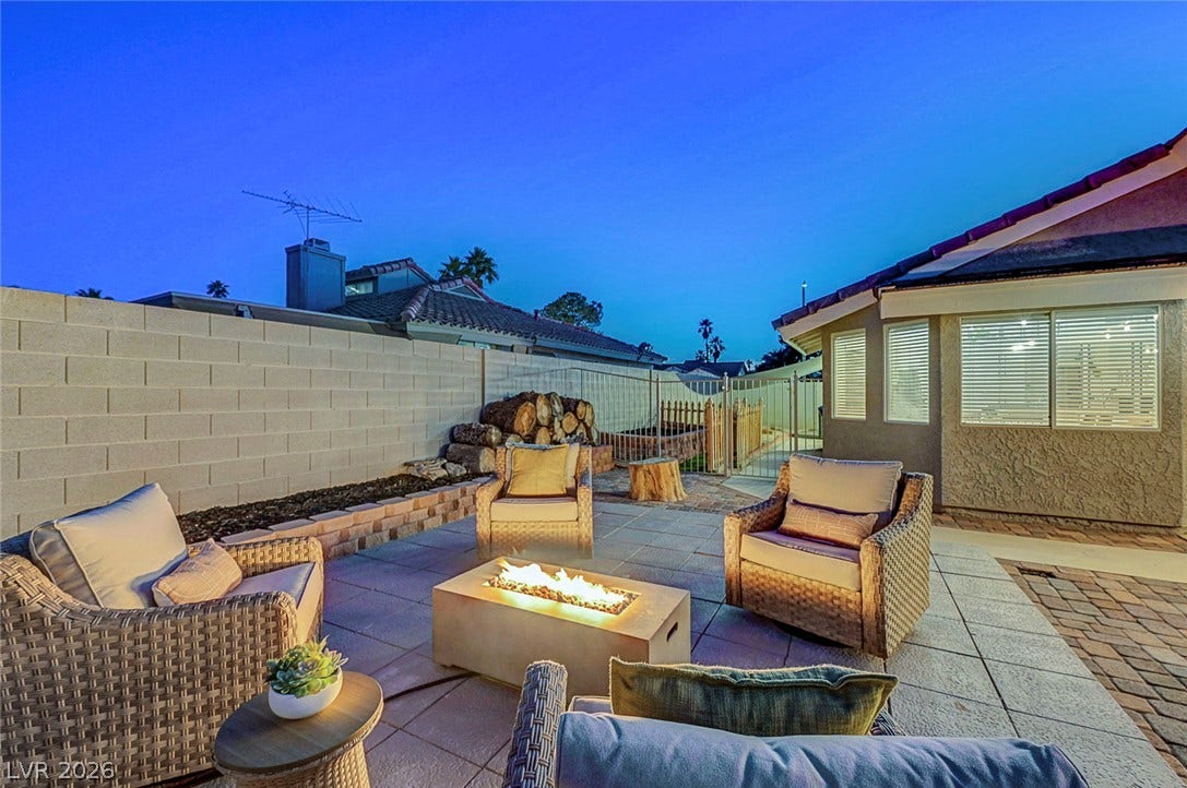 An inviting stone patio offers a cozy fire pit under the evening sky.