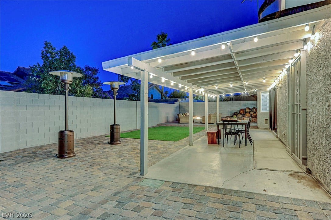 A spacious covered patio integrates seamlessly with paved and grassy outdoor living areas.