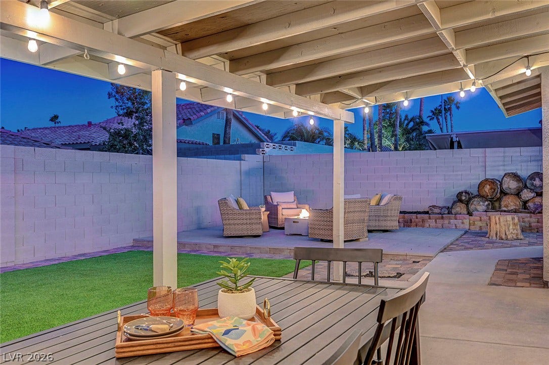 An inviting covered patio opens to a walled backyard featuring a paved lounge area.