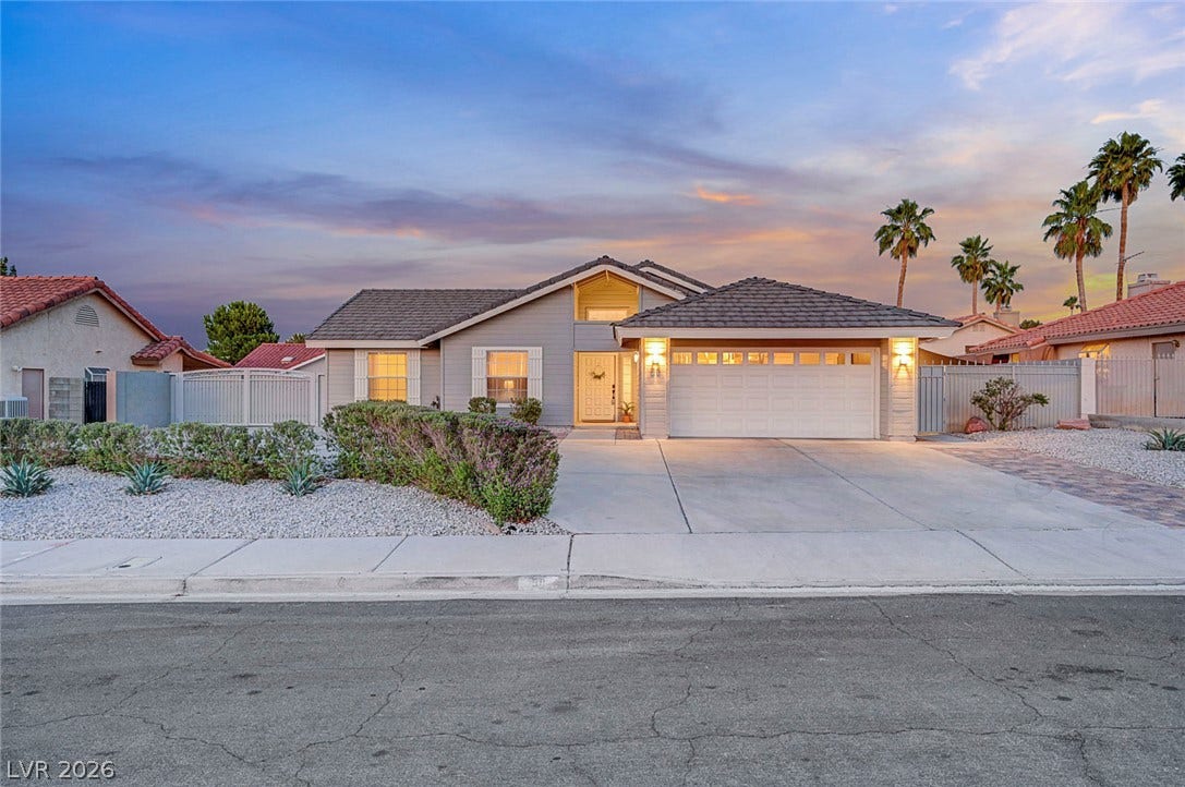 Manicured desert landscaping and a concrete driveway lead to this single-story suburban residence.