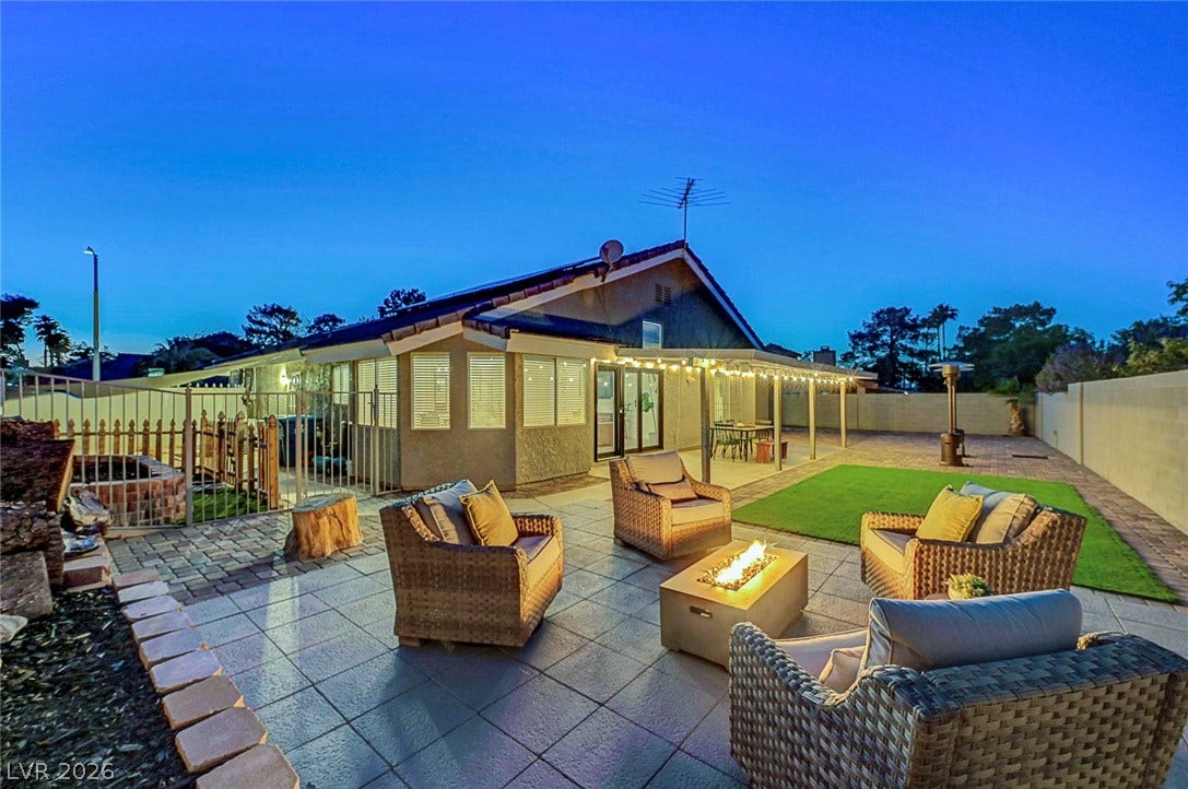 A spacious tiled patio and lawn invite relaxed outdoor living under twilight skies.