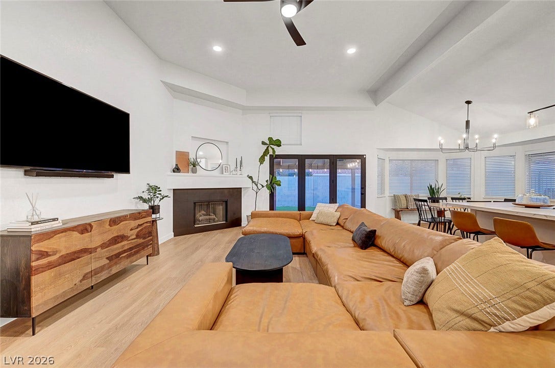 An open living room flows into the dining area under tall tray ceilings.