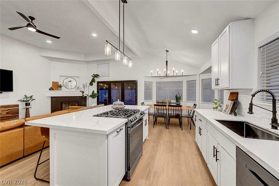 An open floorplan seamlessly connects the contemporary kitchen and dining space under vaulted ceilings.