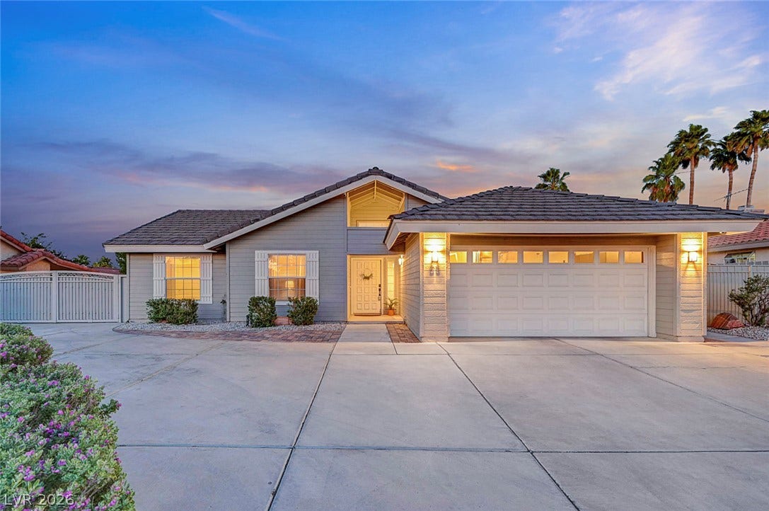 A spacious driveway leads to this single-story home featuring a two-car garage and gabled roofline.