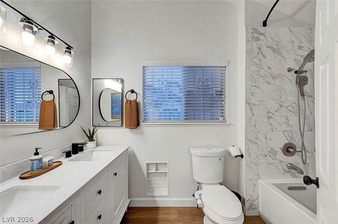 Marble-patterned tile tub surround and a double vanity update this modern bathroom space.