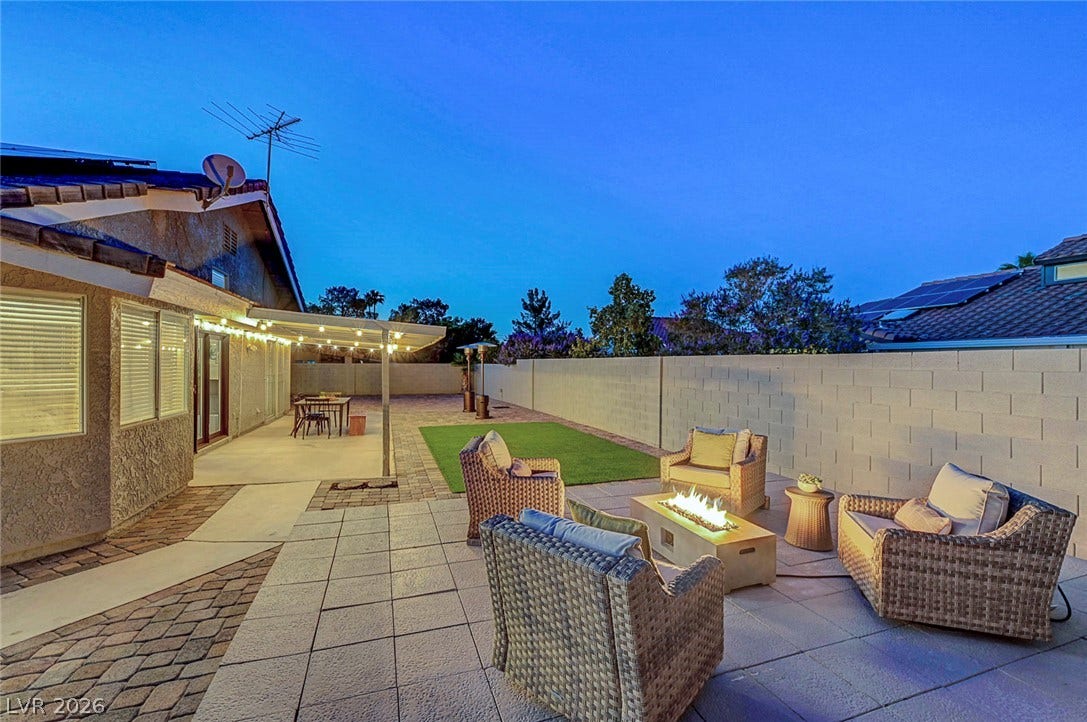 An inviting tiled patio extends to a manicured lawn enclosed by privacy fencing.