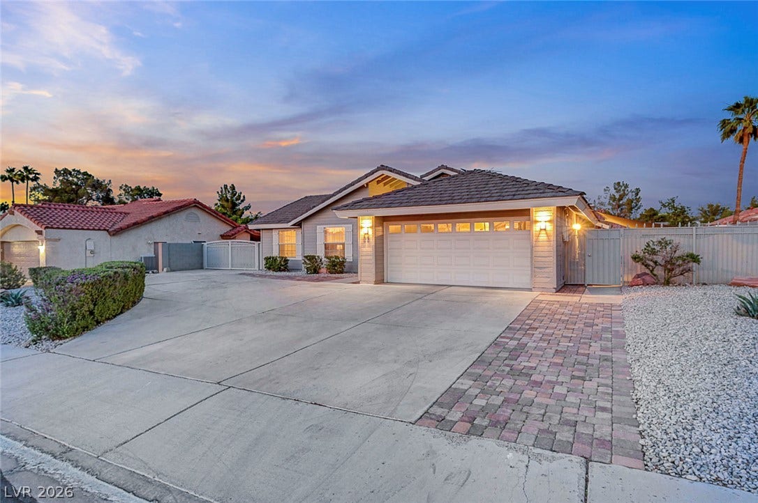 An expansive concrete driveway leads to a classic tile-roof home with an attached garage.