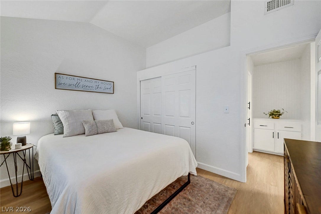 High ceilings and clean wood-style flooring elevate this comfortable bedroom space.