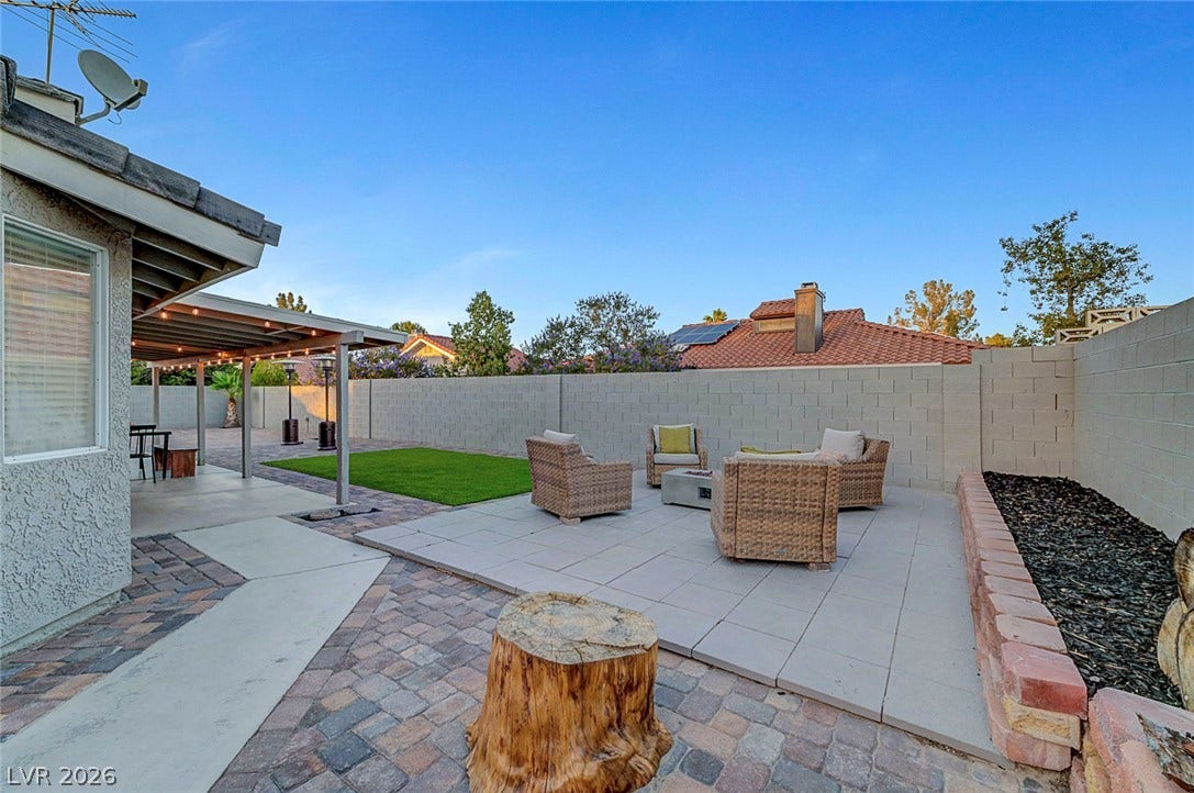 A spacious backyard patio features pavers and concrete under a covered porch area.