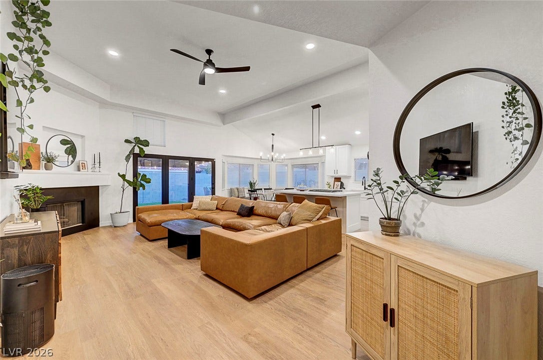 A spacious open-plan layout connects the main living spaces over light-toned wood-style flooring.