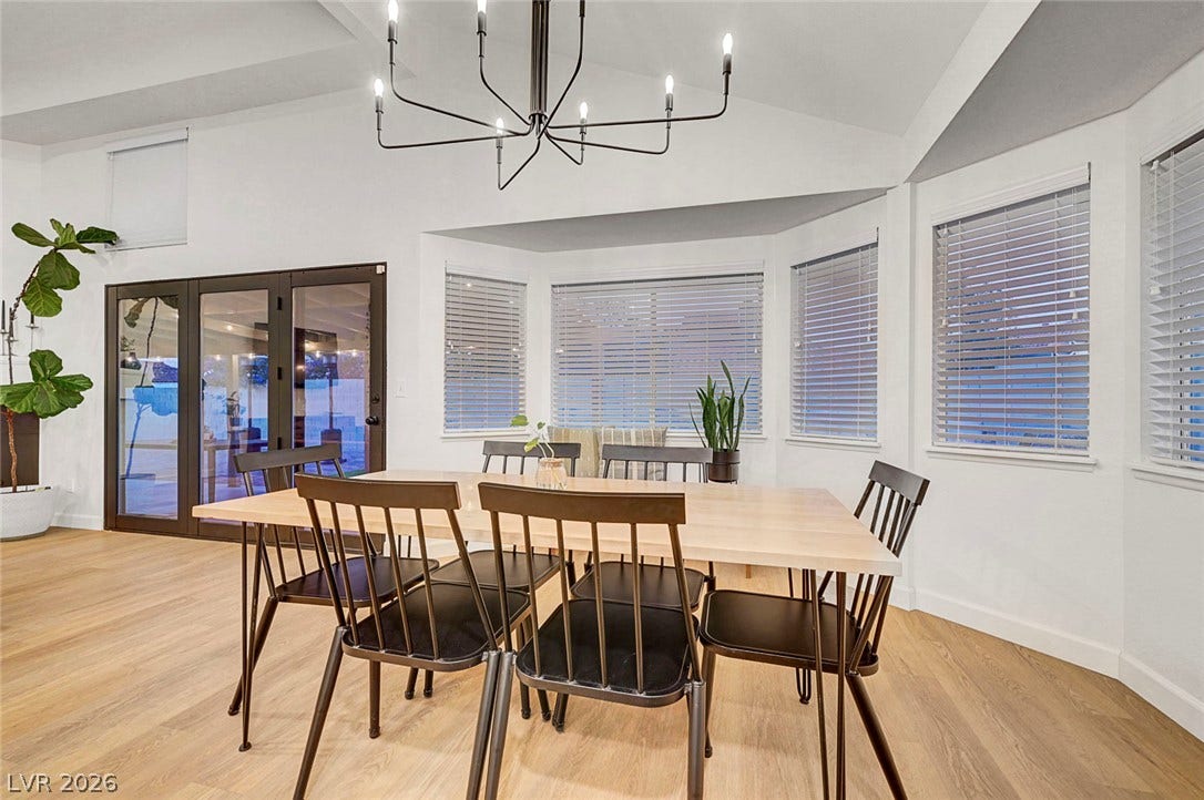 Gleaming wood floors anchor a bright dining area illuminated by a striking modern chandelier.