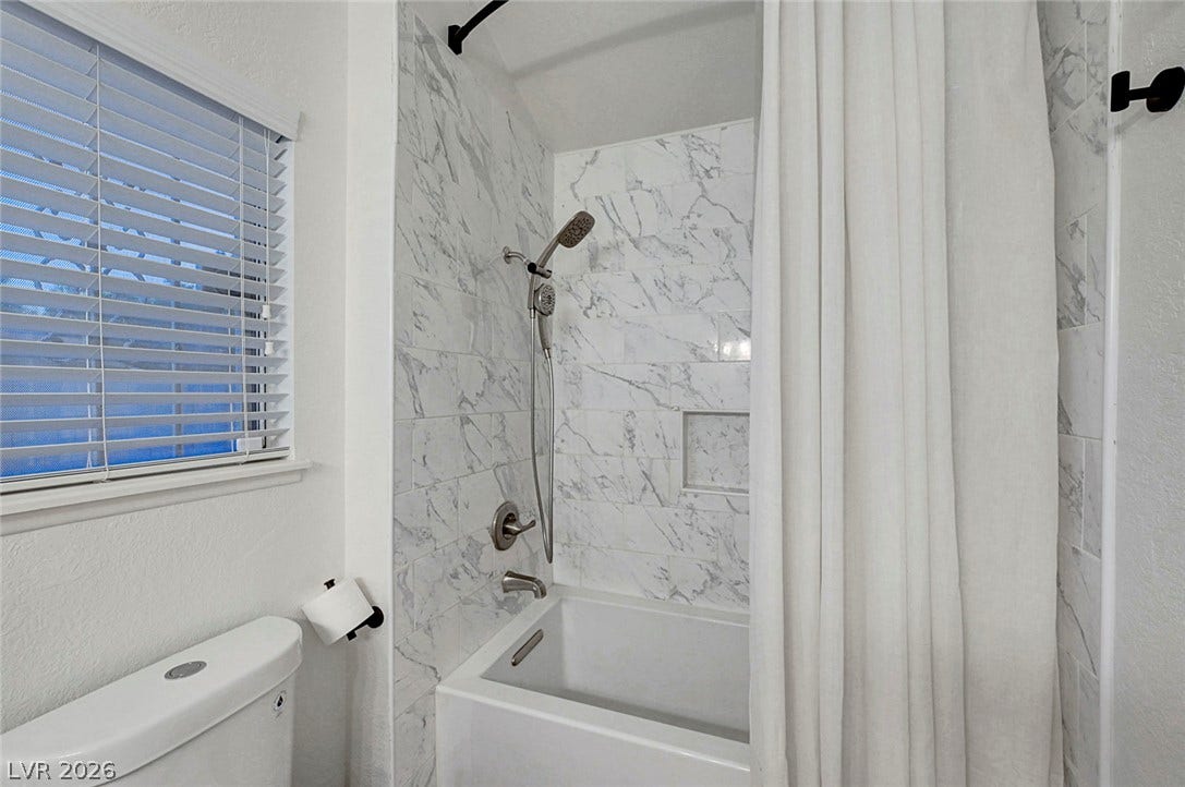 Elegant marble-patterned tile surrounds the modern soaking tub and shower combination.