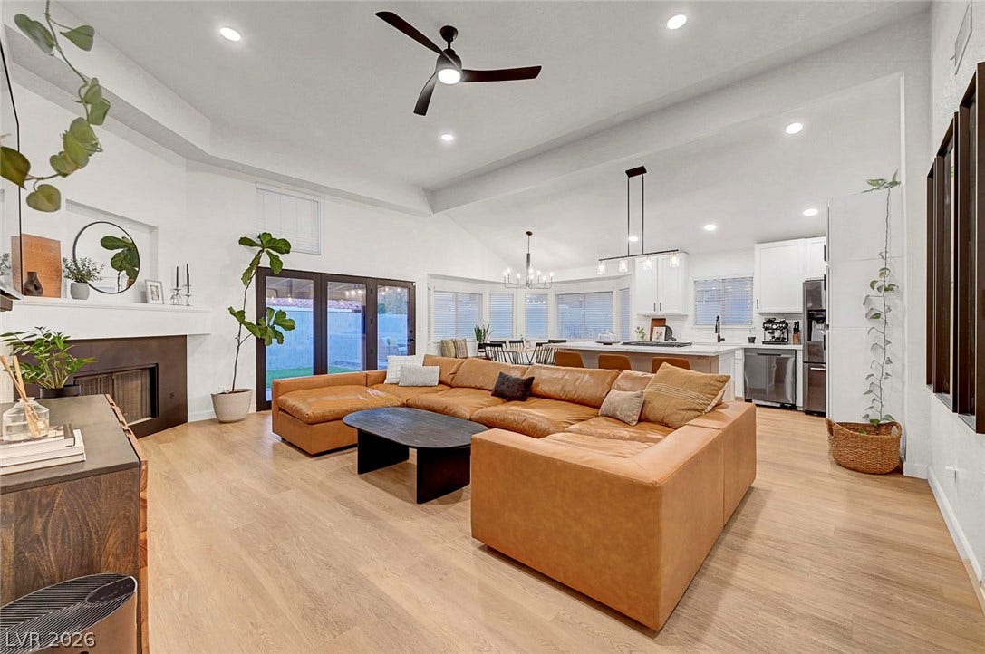 Soaring vaulted ceilings and rich wood floors anchor this expansive open-concept living area.