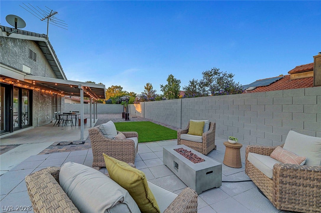 An inviting paved patio area extends into a private backyard enclosed by solid block walls.