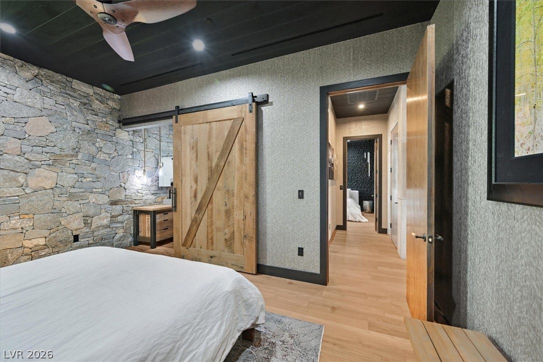4155 Badura Avenue, Las Vegas, NV 89118 Natural stone accent walls and rich wood floors bring organic warmth to this bedroom.