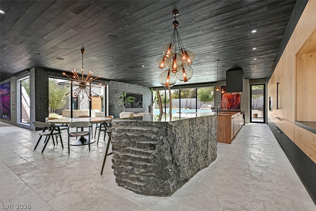 4155 Badura Avenue, Las Vegas, NV 89118 A massive stone island anchors this modern kitchen under dark wood paneled ceilings.