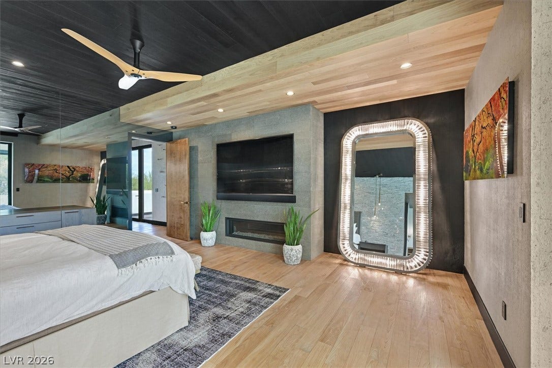 4155 Badura Avenue, Las Vegas, NV 89118 A striking modern fireplace and warm wood flooring define this elegant primary suite.