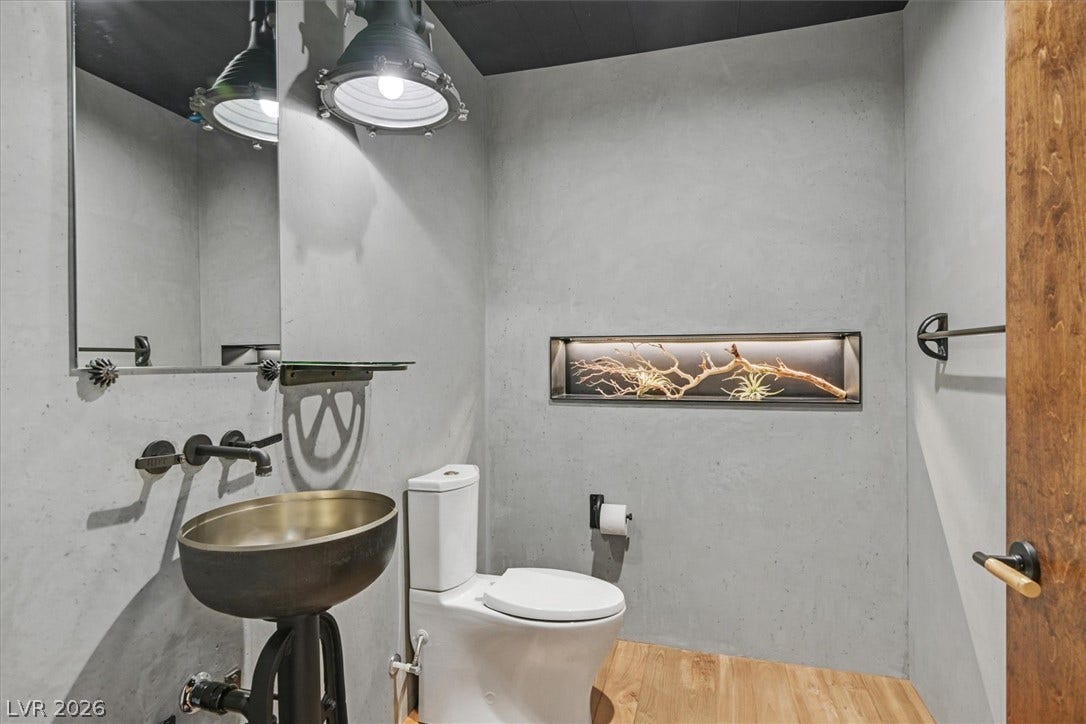 4155 Badura Avenue, Las Vegas, NV 89118 Industrial style shapes this unique powder room featuring sleek concrete walls and warm wood flooring.