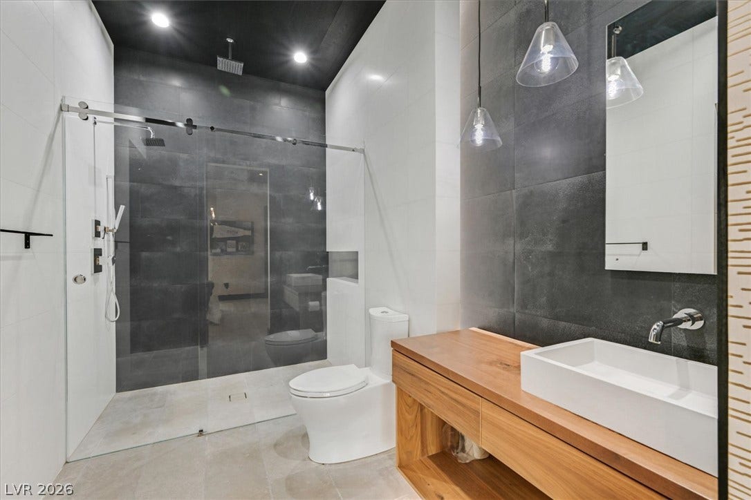 4155 Badura Avenue, Las Vegas, NV 89118 Dark tile accents and a glass-enclosed shower highlight this modern bathroom space.