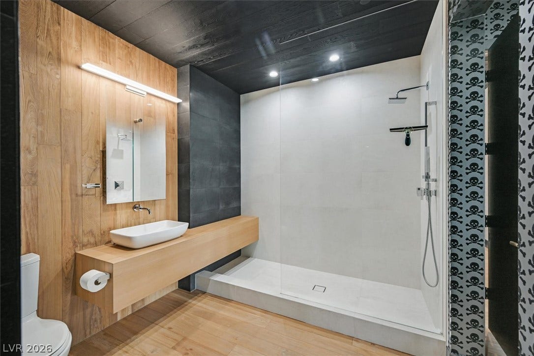 4155 Badura Avenue, Las Vegas, NV 89118 Warm wood wall paneling and a sleek walk-in shower define this contemporary bathroom space.