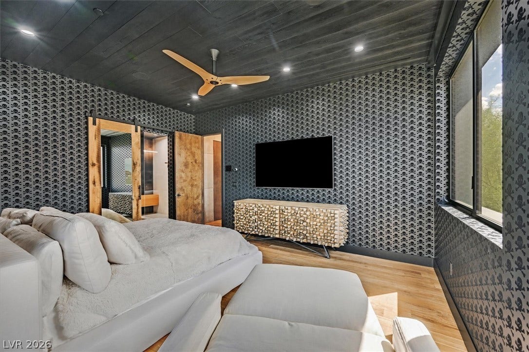 4155 Badura Avenue, Las Vegas, NV 89118 Bold patterned walls and a dark wood ceiling frame this modern bedroom with hardwood flooring.