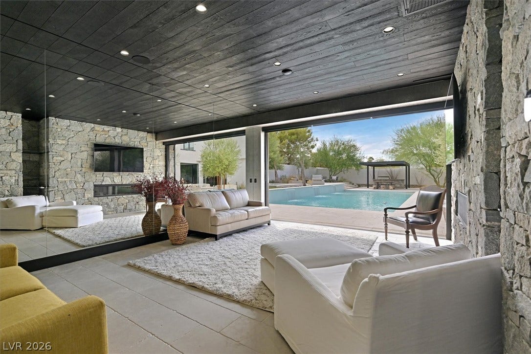 4155 Badura Avenue, Las Vegas, NV 89118 Rich stone walls and a dark wood ceiling frame the indoor-outdoor transition to the pool.
