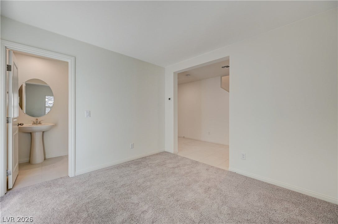 Plush carpeting and crisp white walls define this versatile space adjacent to a powder room.