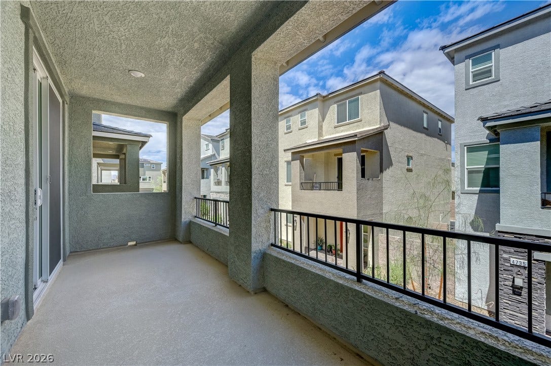 Covered concrete balcony framed by stucco columns overlooks the surrounding neighborhood.