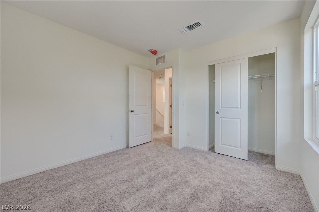 Plush carpeting and a built-in closet define this versatile secondary bedroom space.