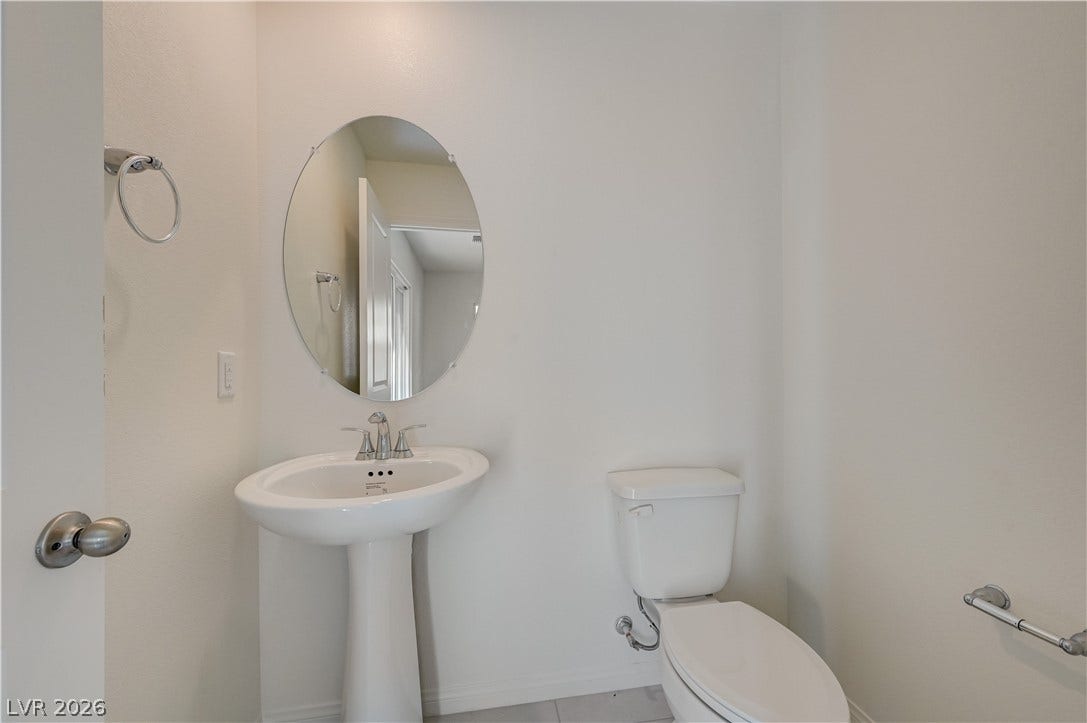 A classic pedestal sink paired with clean neutral walls defines this half bath.