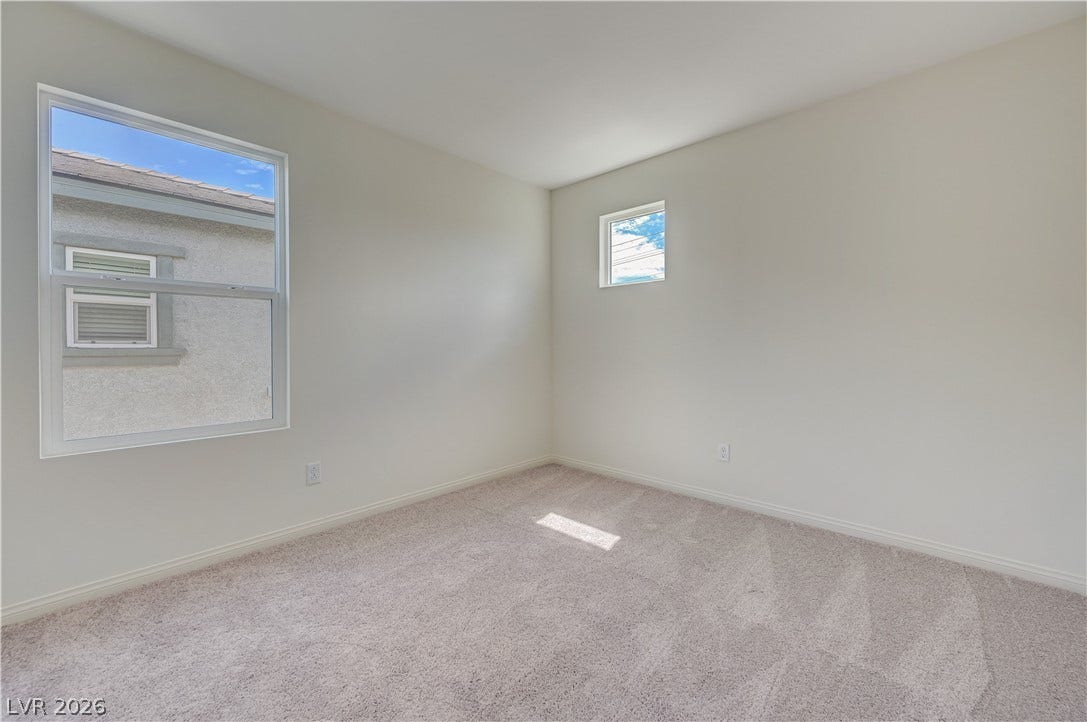 Natural light fills a carpeted bedroom featuring clean lines and neutral walls.