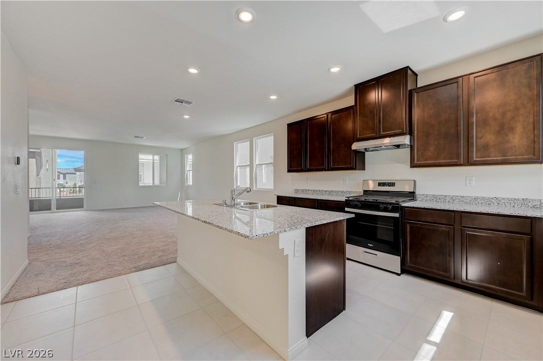 Gleaming stone countertops and dark wood cabinetry define this modern open-concept culinary space.
