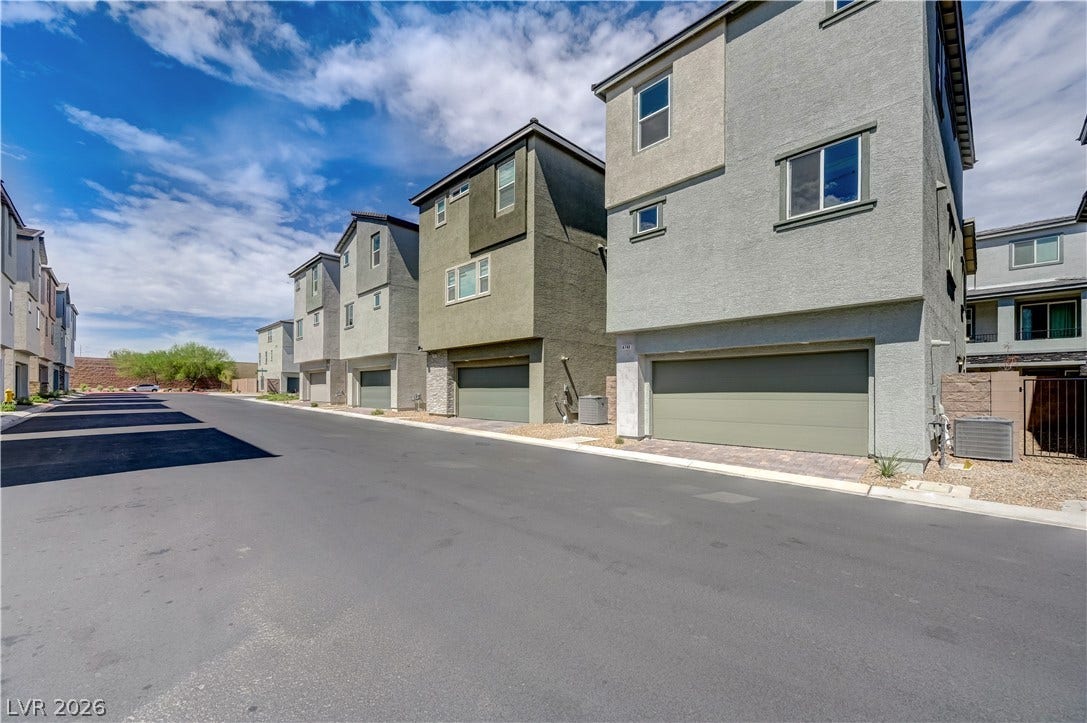 Multi-level modern townhomes line a quiet paved street under wide desert skies.