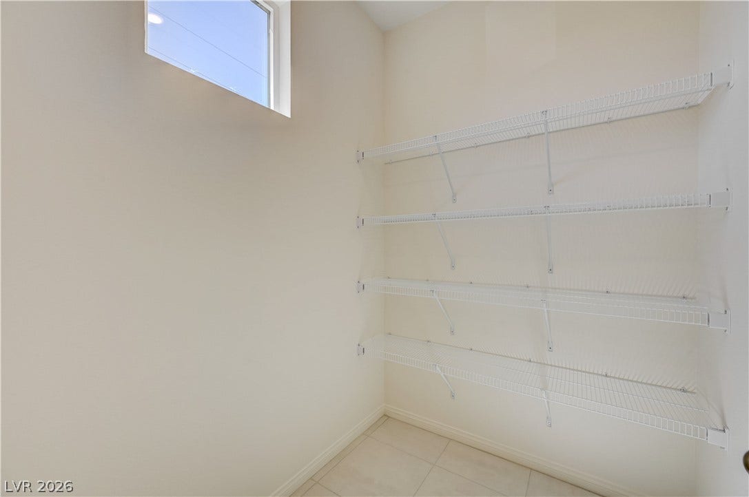 Tiled flooring and natural light from a high window elevate this functional storage area.